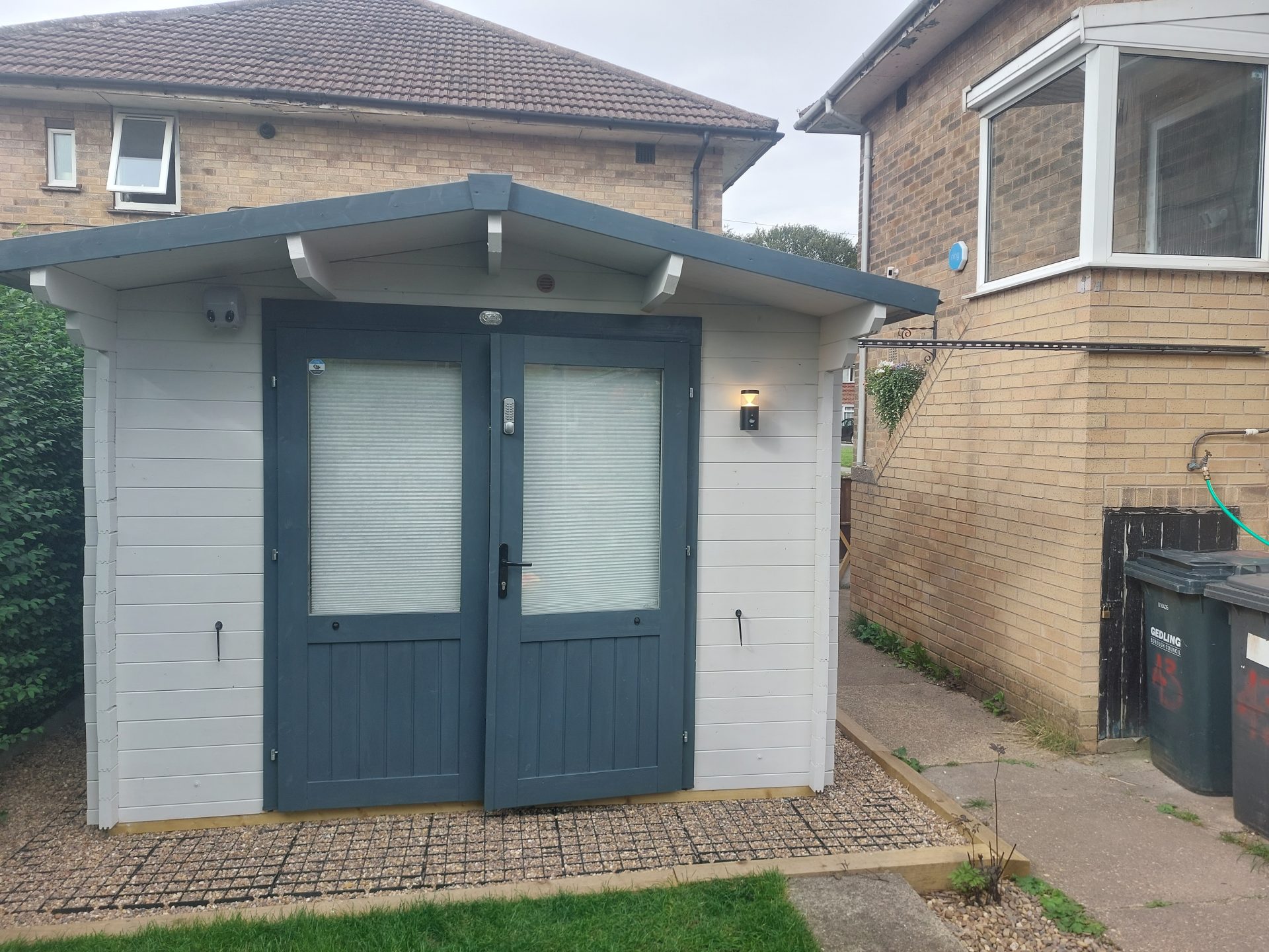 Timber outbuilding with an exterior wall light powered from a new supply