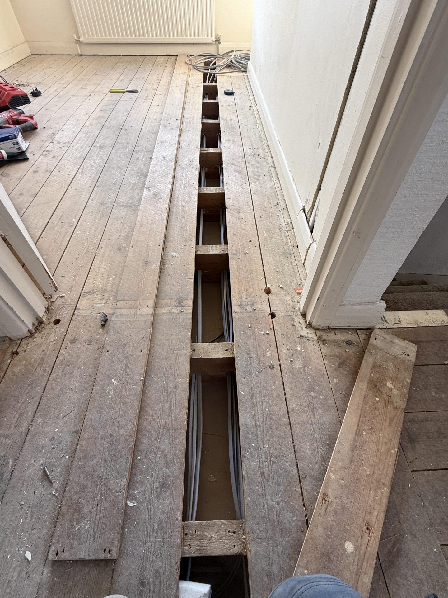 New cables routed under lifted floorboards during a full house rewire in Nottingham